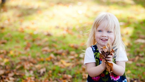 A young child playing in the autumn leaves
